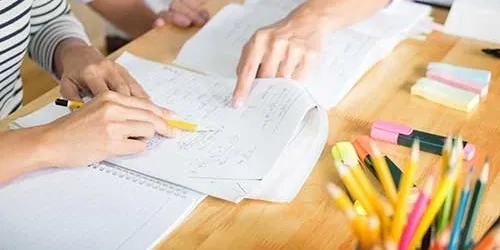 Two people studying with books and pencils.
