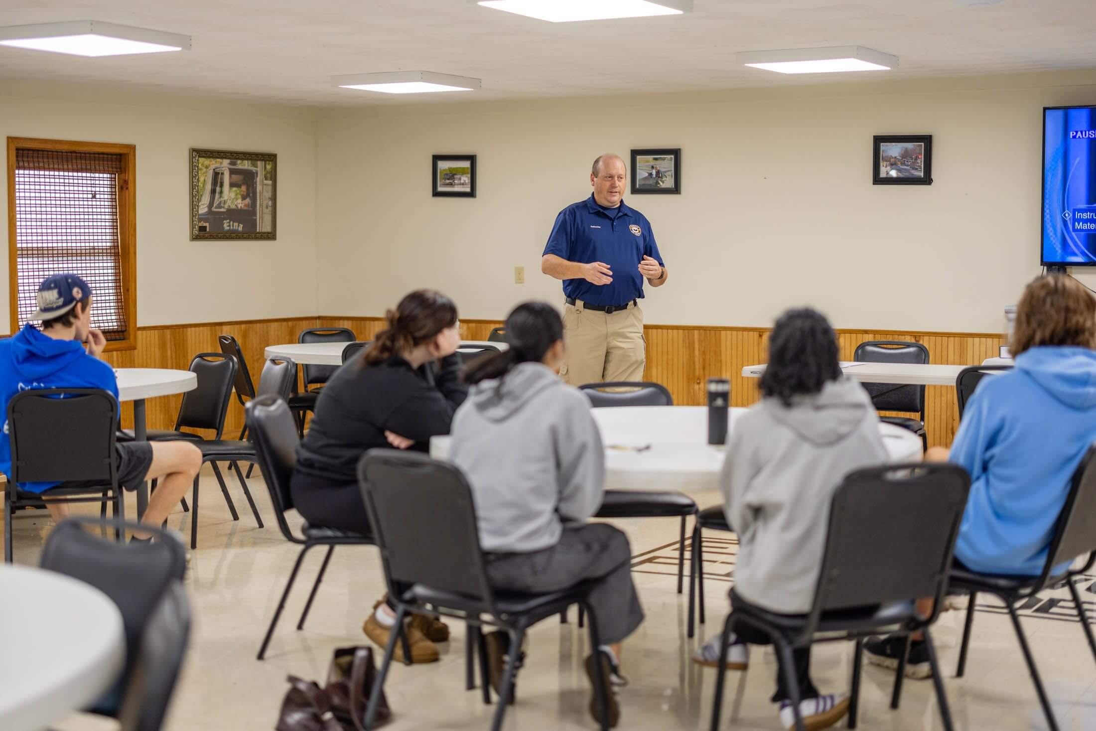 Instructor speaking to students in classroom setting.